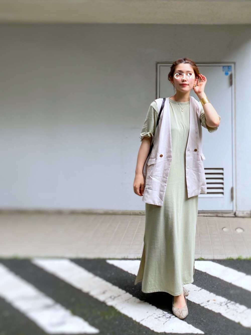 グリーン系のワンピース、ベージュ系のベスト、ブラウン系のトートバッグを着用したレディースの春コーディネートの1枚目の写真