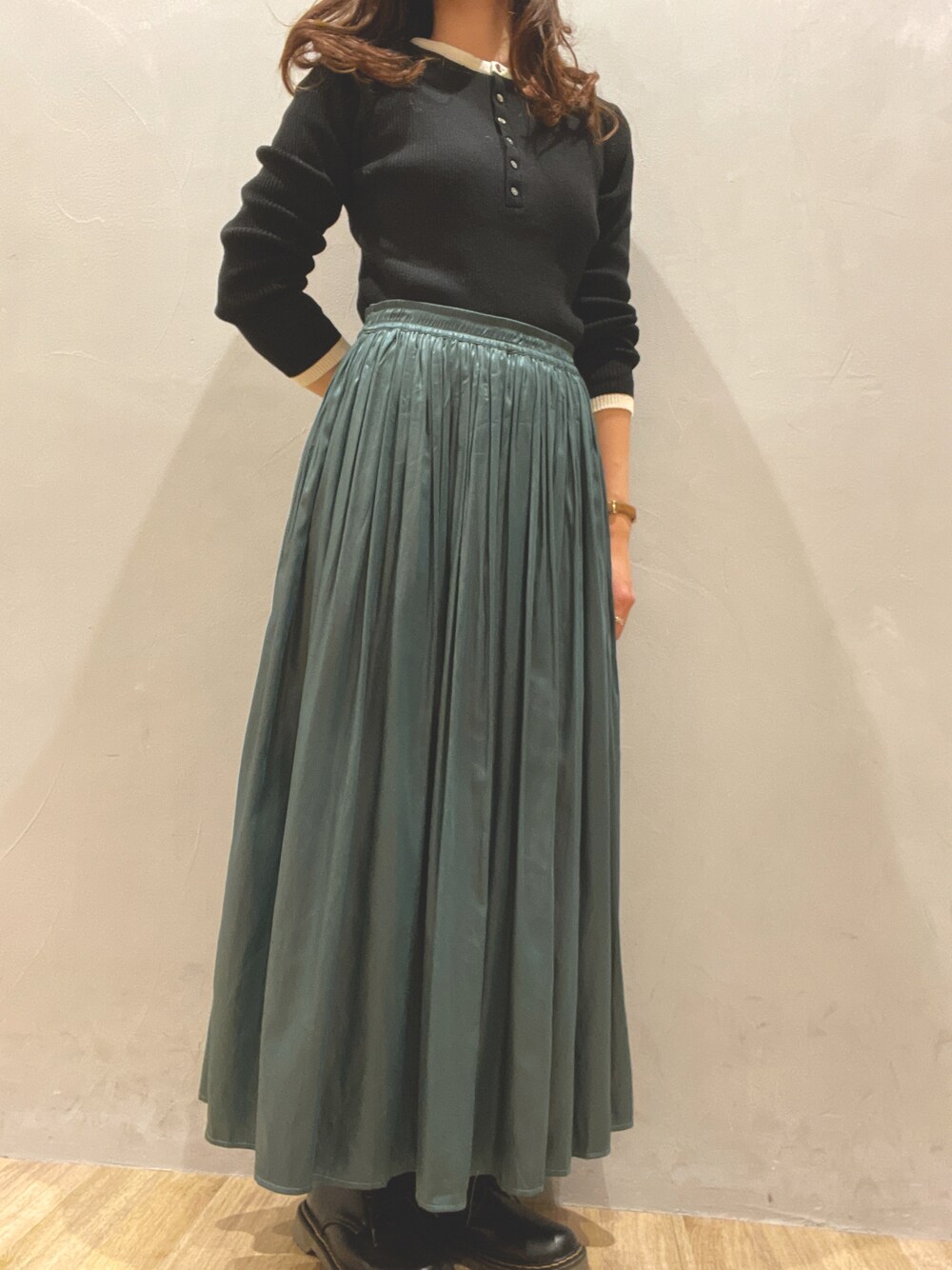 グリーン系のスカート、ブラック系のニット/セーター、ブラック系のドレスシューズを着用したレディースの冬コーディネートの1枚目の写真