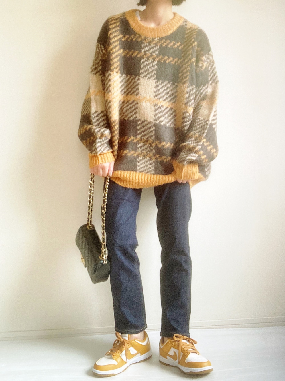 イエロー系のニット/セーター、ブルー系のデニムパンツ、ベージュ系のスニーカーを着用したレディースの秋コーディネートの1枚目の写真