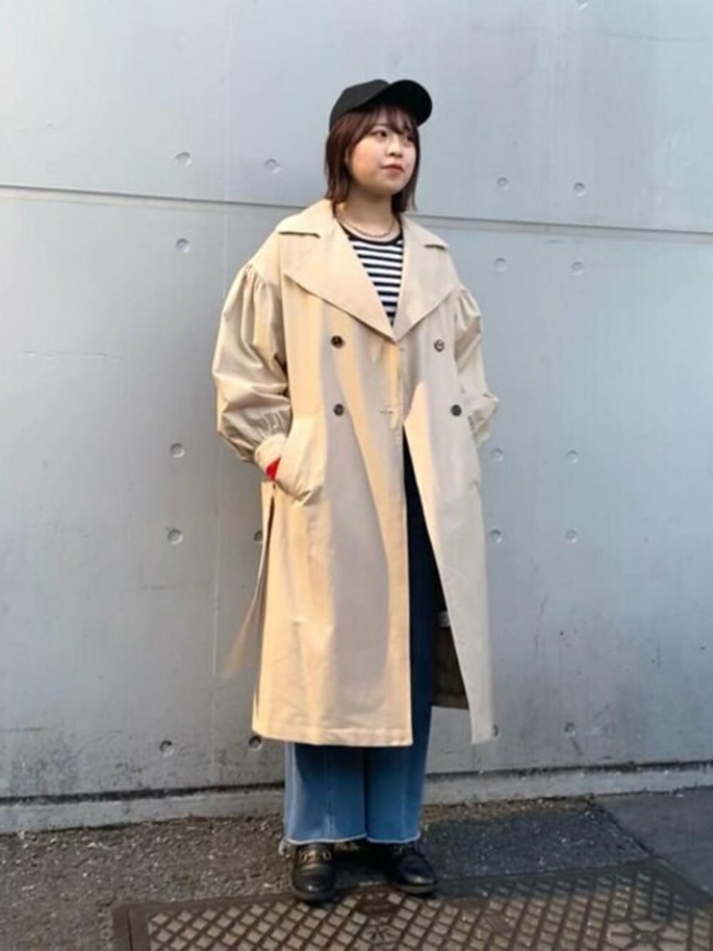 レッド系のカーディガン/ボレロ、ブルー系のデニムパンツ、ベージュ系のトレンチコートを着用したレディースの冬コーディネートの1枚目の写真