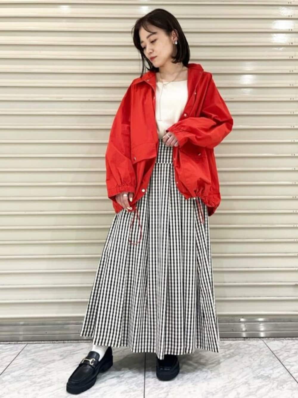 レッド系のブルゾン、ベージュ系のTシャツ/カットソー、ブラック系のスカートを着用したレディースの春コーディネートの1枚目の写真