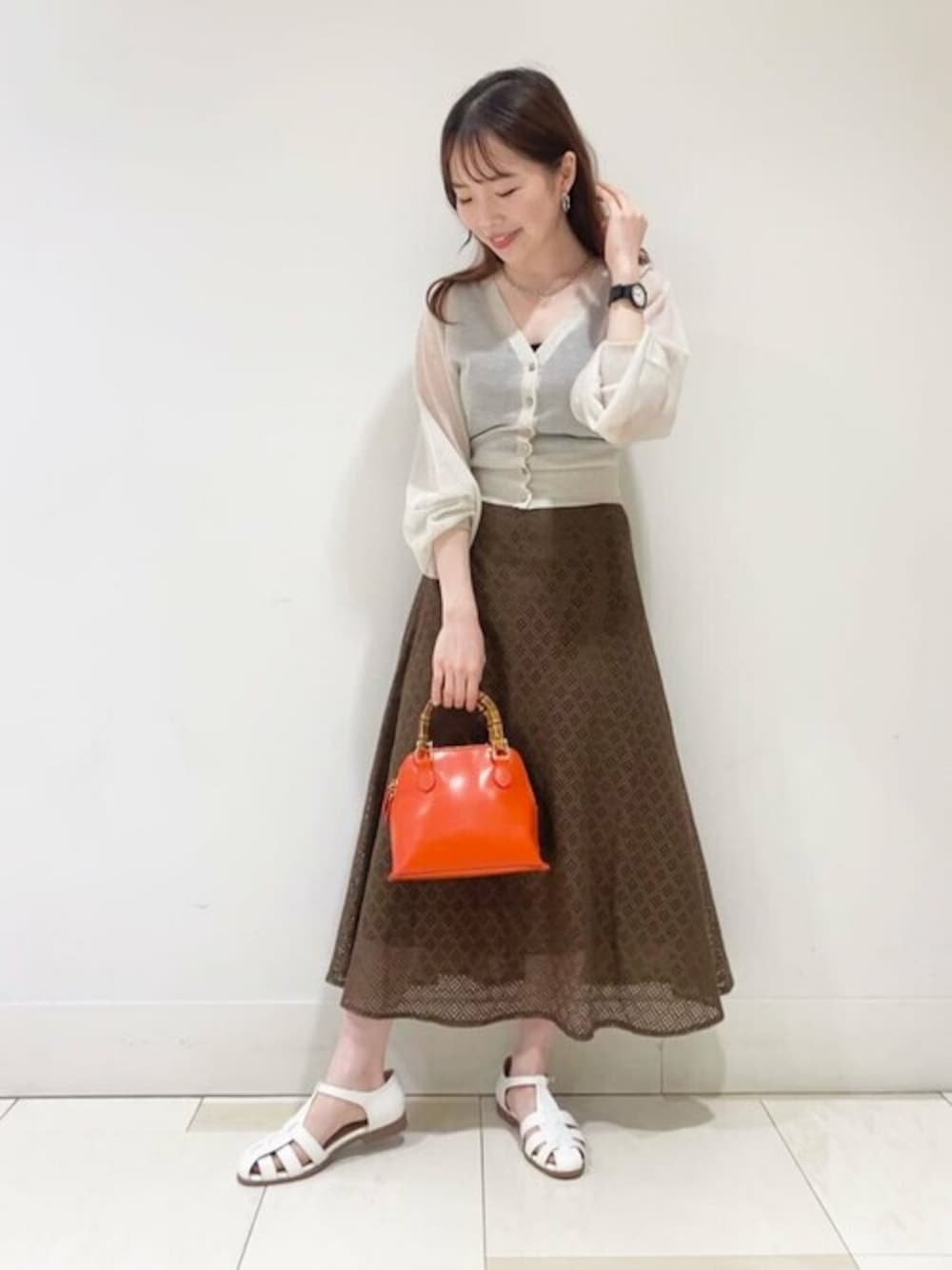 ブラウン系のスカート、ホワイト系のサンダル、ホワイト系のカーディガン/ボレロを着用したレディースの春コーディネートの1枚目の写真