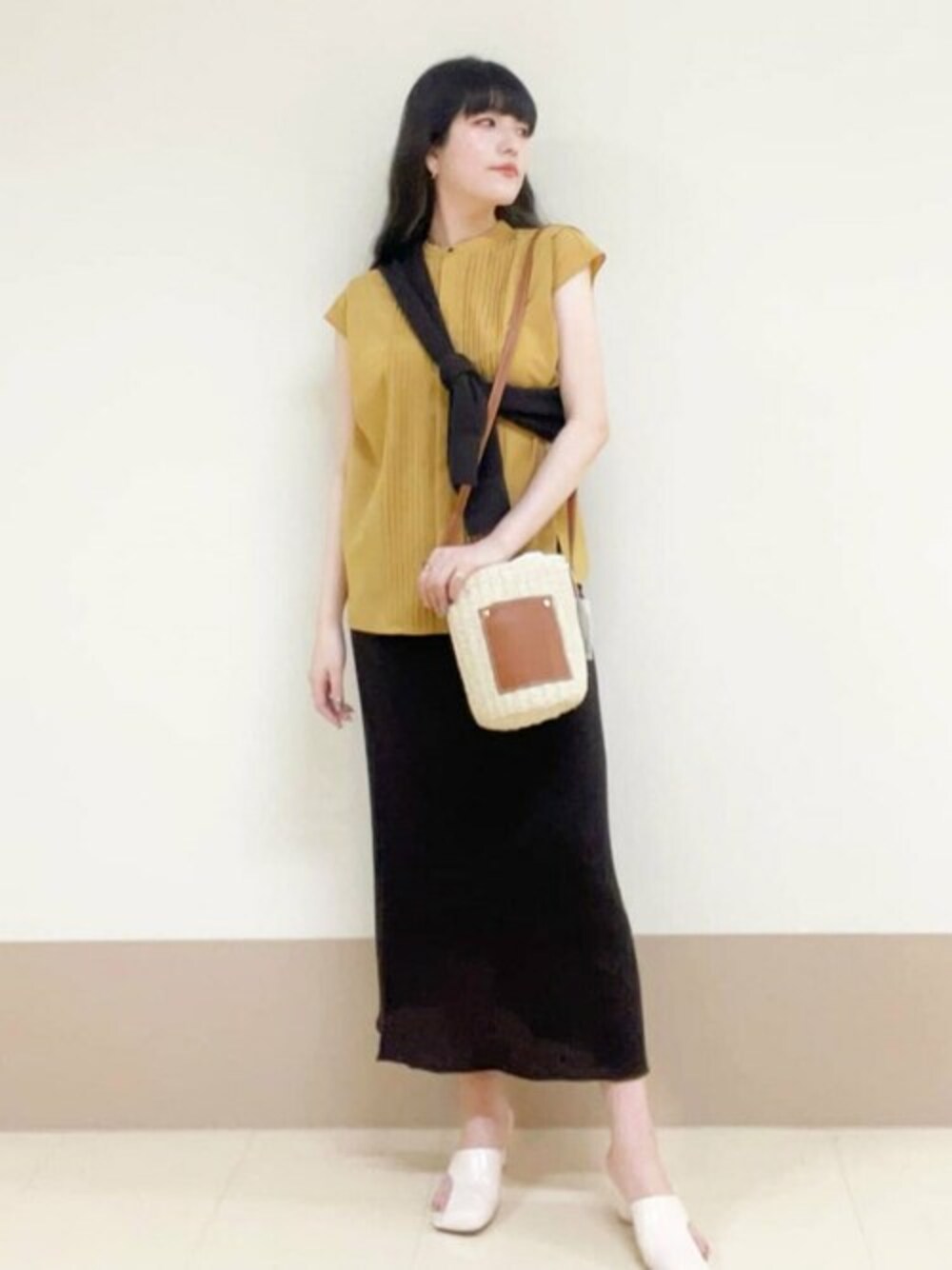 イエロー系のシャツ/ブラウス、ブラウン系のニット/セーター、ベージュ系のトートバッグを着用したレディースの春コーディネートの1枚目の写真