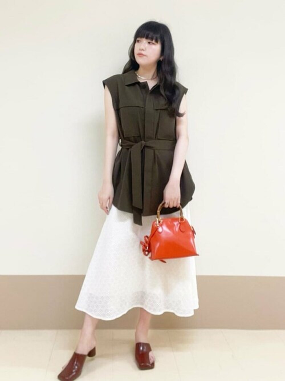 ブラウン系のその他アウター、ホワイト系のスカート、オレンジ系のショルダーバッグを着用したレディースの春コーディネートの1枚目の写真