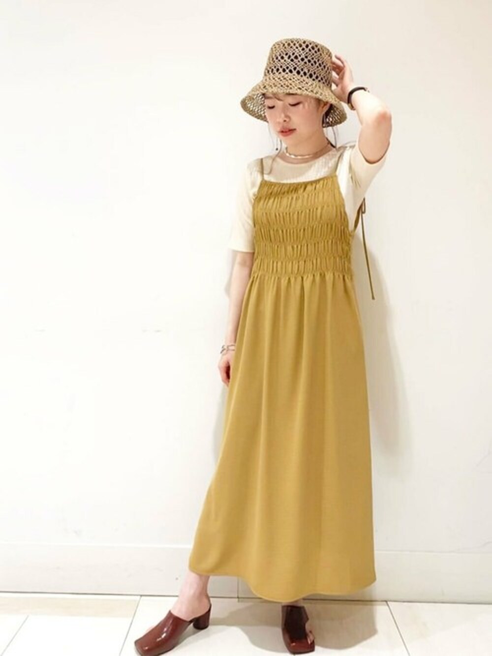 イエロー系のワンピース、ホワイト系のTシャツ/カットソー、ベージュ系のサンダルを着用したレディースの春コーディネートの1枚目の写真
