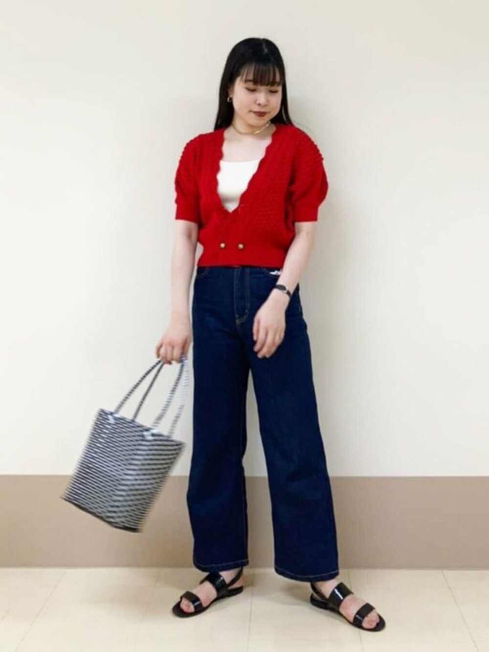 ホワイト系のタンクトップ、レッド系のカーディガン/ボレロ、ブルー系のデニムパンツを着用したレディースの春コーディネートの1枚目の写真