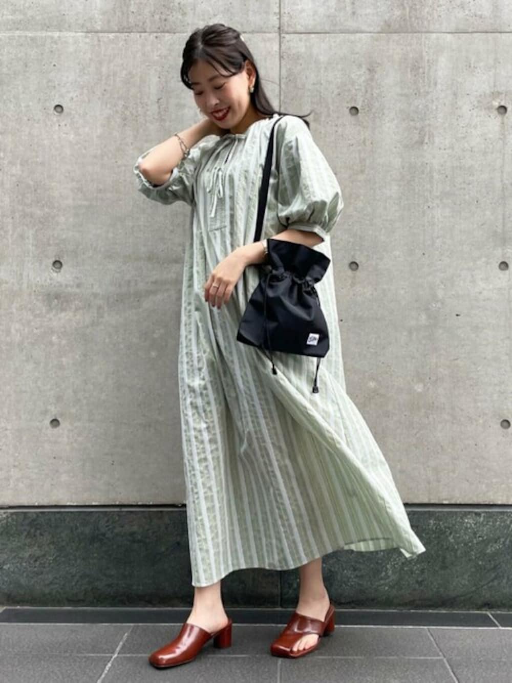 グリーン系のワンピース、ブラック系のショルダーバッグ、ブラウン系のサンダルを着用したレディースの春コーディネートの1枚目の写真