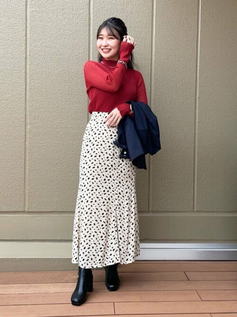 レッド系のニット/セーター、ホワイト系のスカート、ブルー系のテーラードジャケットを着用したレディースの夏コーディネートの1枚目の写真