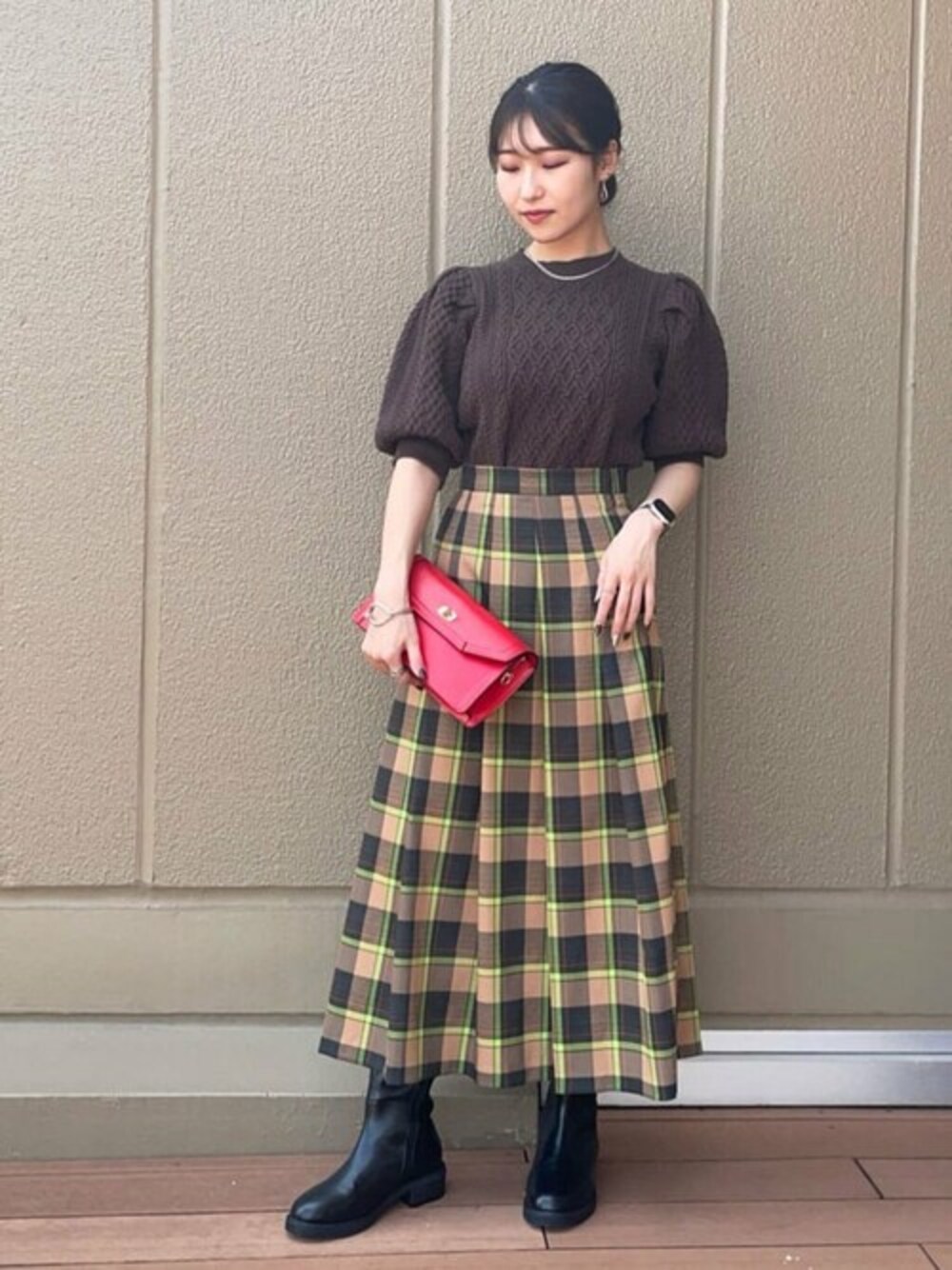 ブラウン系のニット/セーター、ベージュ系のスカート、ブラック系のブーツを着用したレディースの秋コーディネートの1枚目の写真