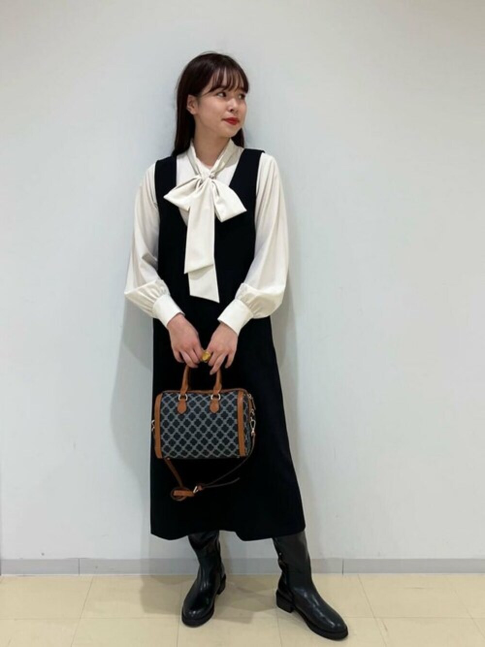 ブラック系のジャンパースカート、ホワイト系のシャツ/ブラウス、ブラック系のブーツを着用したレディースの秋コーディネートの1枚目の写真