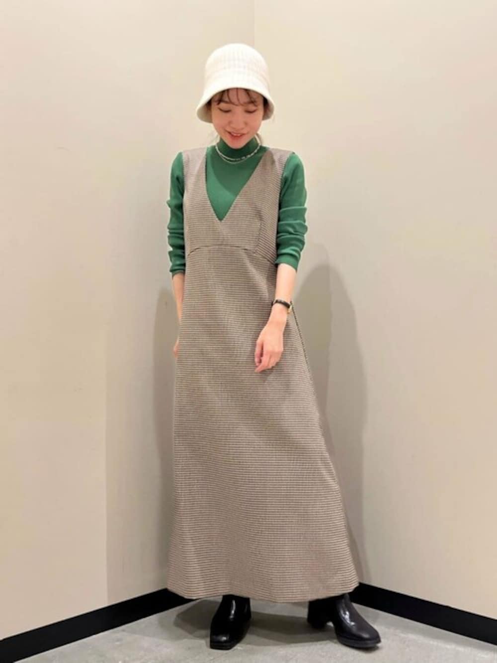 ブラウン系のジャンパースカート、グリーン系のニット/セーターを着用したレディースの秋コーディネートの1枚目の写真
