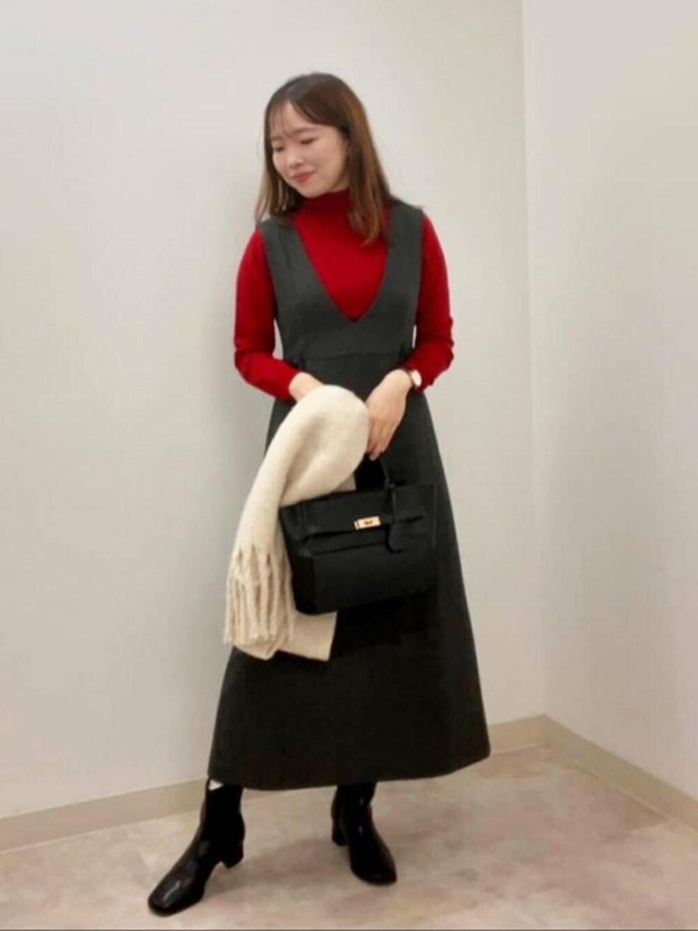 レッド系のニット/セーター、ブラック系のブーツ、ブラック系のトートバッグを着用したレディースの秋コーディネートの1枚目の写真
