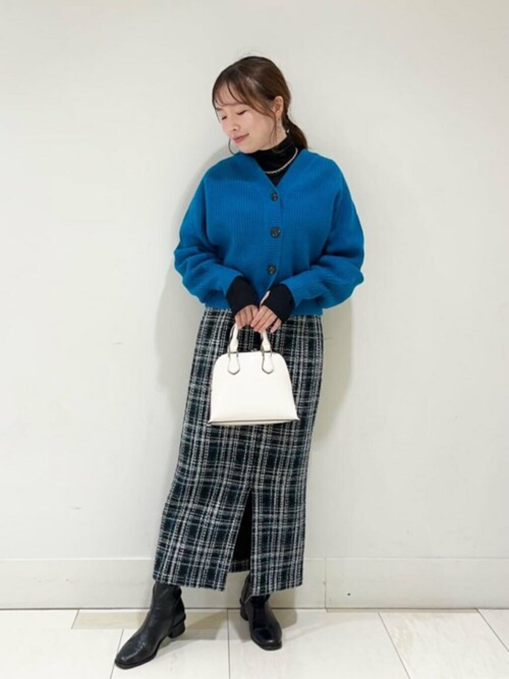 ブルー系のカーディガン/ボレロ、ブラック系のTシャツ/カットソー、グリーン系のスカートを着用したレディースの秋コーディネートの1枚目の写真