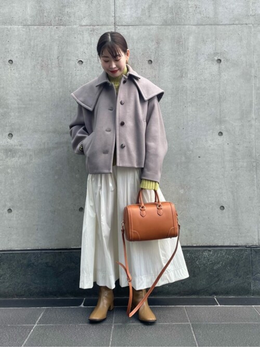 グリーン系のニット/セーター、ホワイト系のスカート、ブラウン系のステンカラーコートを着用したレディースの冬コーディネートの1枚目の写真