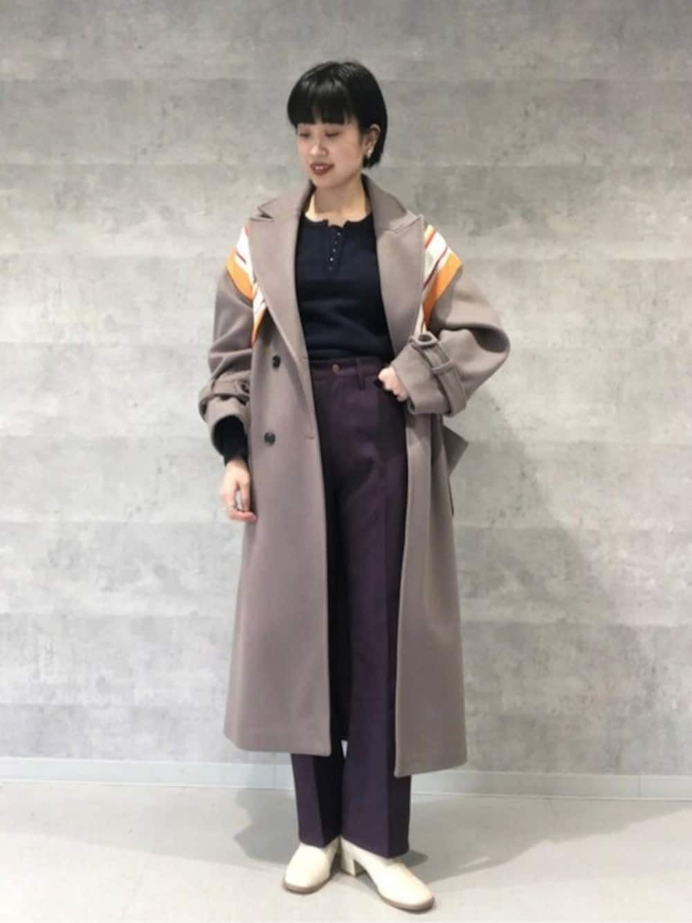 ブラウン系のチェスターコート、ブルー系のニット/セーター、ホワイト系のブーツを着用したレディースの冬コーディネートの1枚目の写真