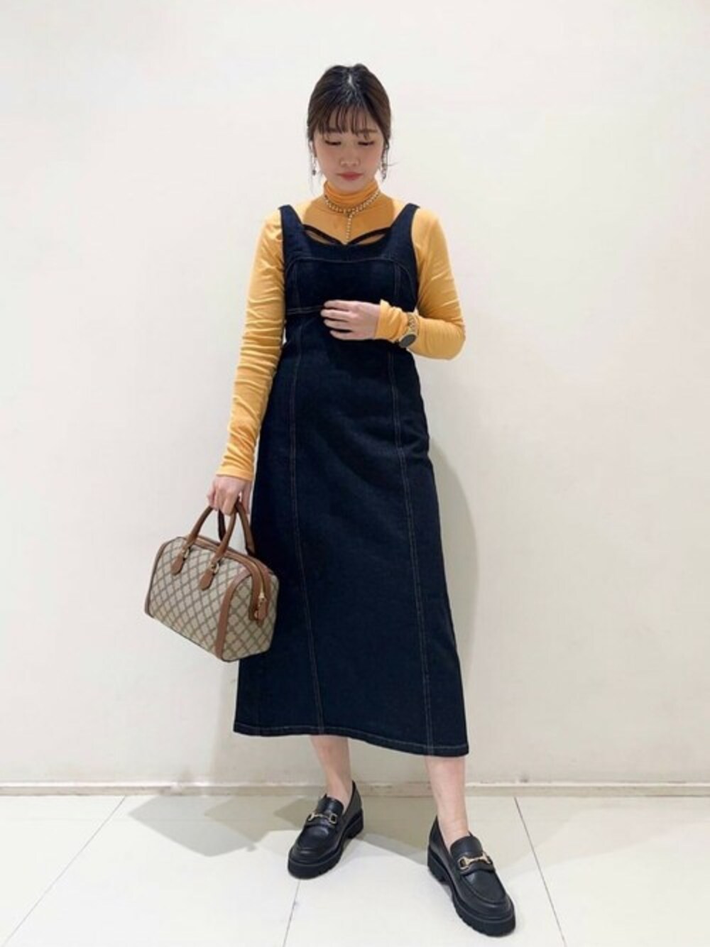 ブルー系のワンピース、オレンジ系のTシャツ/カットソー、ブラック系のパンプスを着用したレディースの冬コーディネートの1枚目の写真