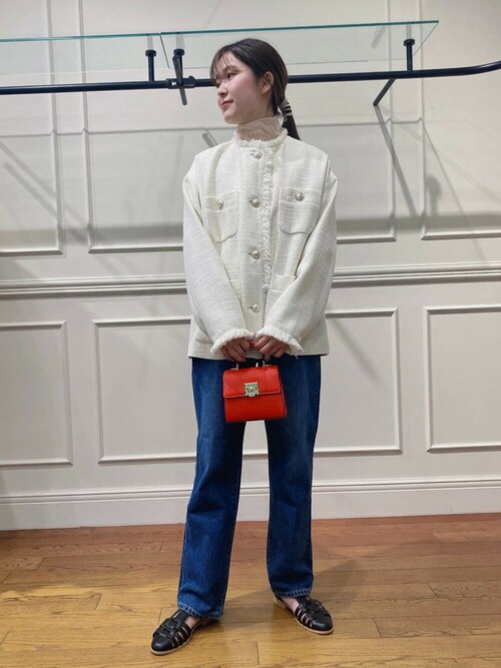 ホワイト系のノーカラージャケット、ブルー系のデニムパンツ、レッド系のショルダーバッグを着用したレディースの冬コーディネートの1枚目の写真