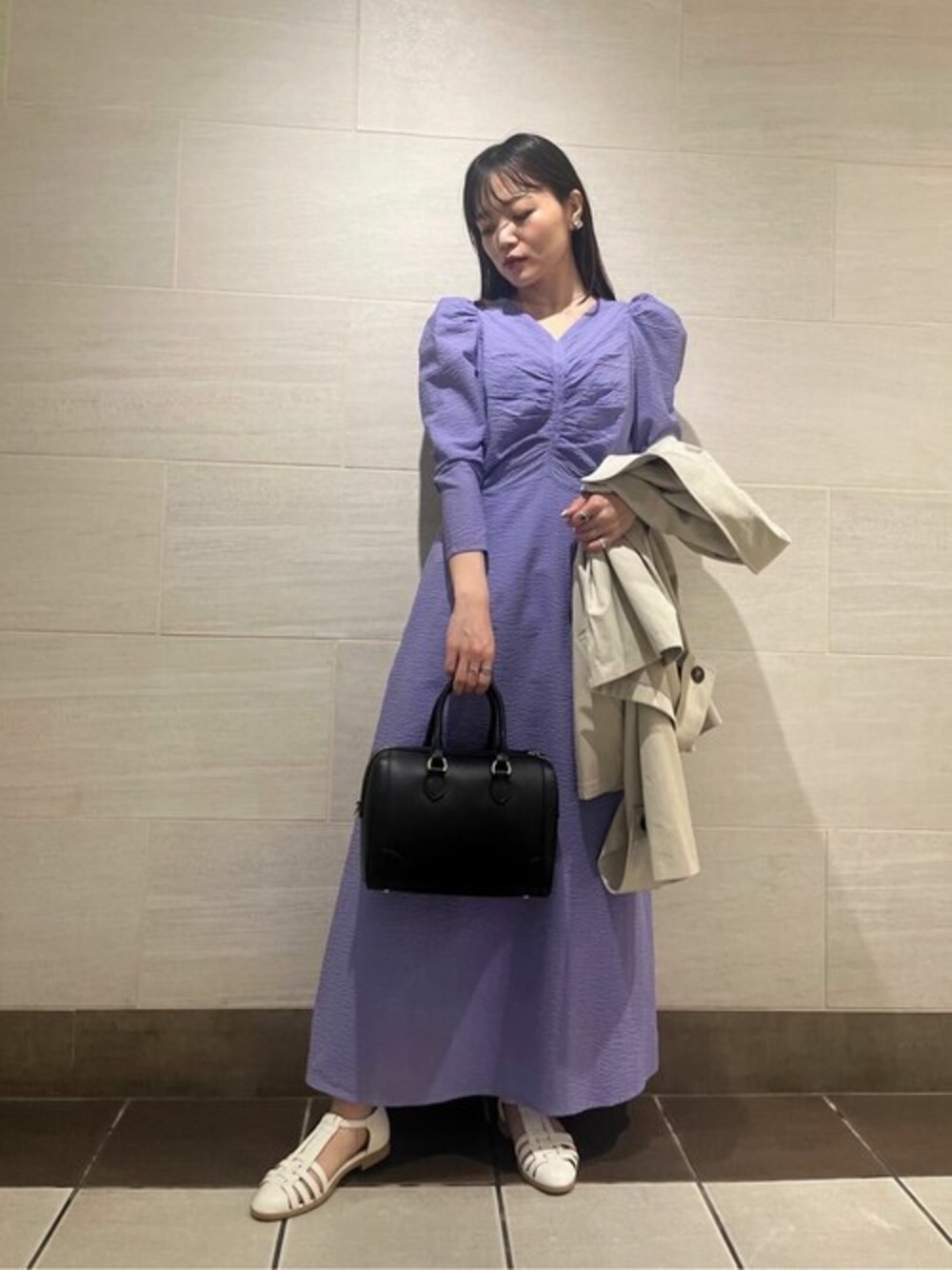パープル系のワンピース、ホワイト系のサンダル、ホワイト系のトレンチコートを着用したレディースの冬コーディネートの1枚目の写真