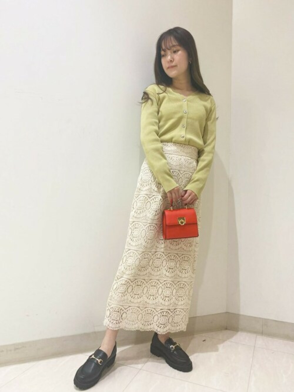 イエロー系のカーディガン/ボレロ、ホワイト系のスカート、レッド系のショルダーバッグを着用したレディースの春コーディネートの1枚目の写真