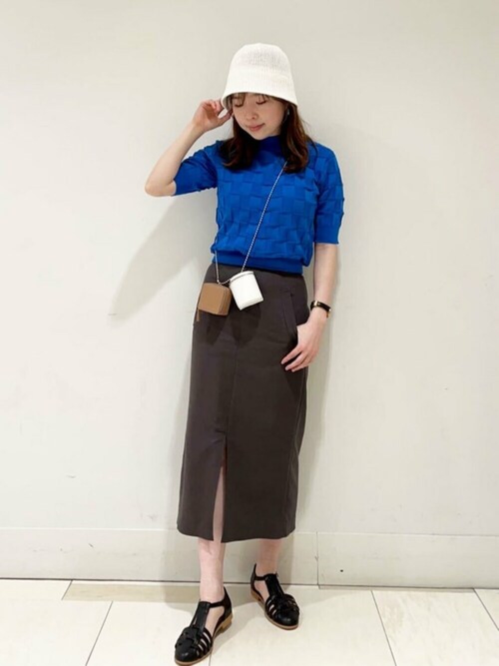 グレー系のスカート、ブルー系のニット/セーター、ブラック系のサンダルを着用したレディースの春コーディネートの1枚目の写真