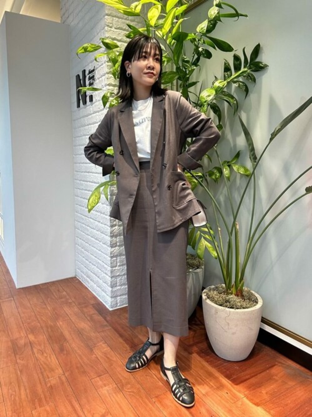 グレー系のスカート、グレー系のテーラードジャケット、ホワイト系のTシャツ/カットソーを着用したレディースの春コーディネートの1枚目の写真