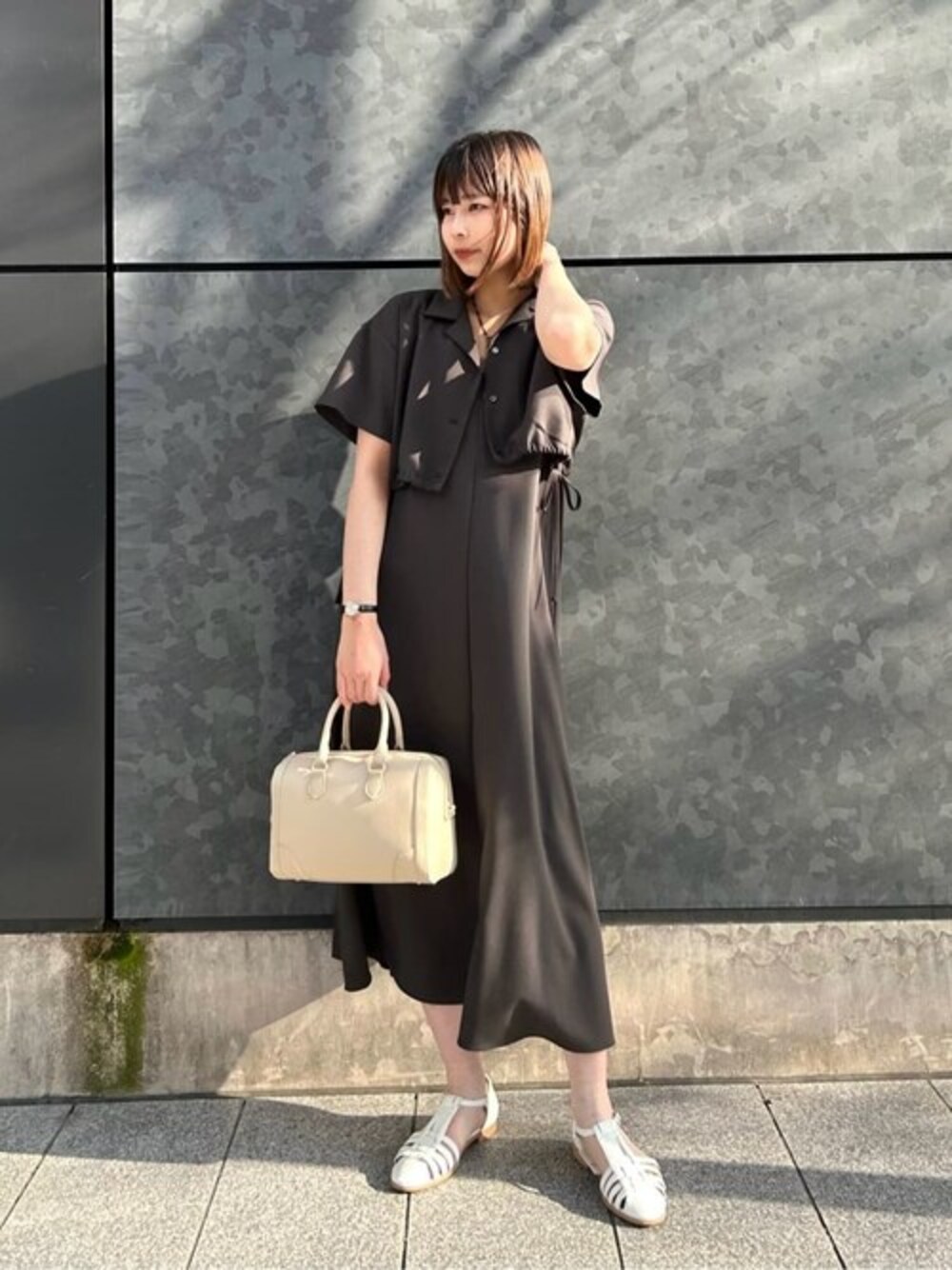 グレー系のワンピース、ブラウン系のタンクトップ、ベージュ系のトートバッグを着用したレディースの春コーディネートの1枚目の写真