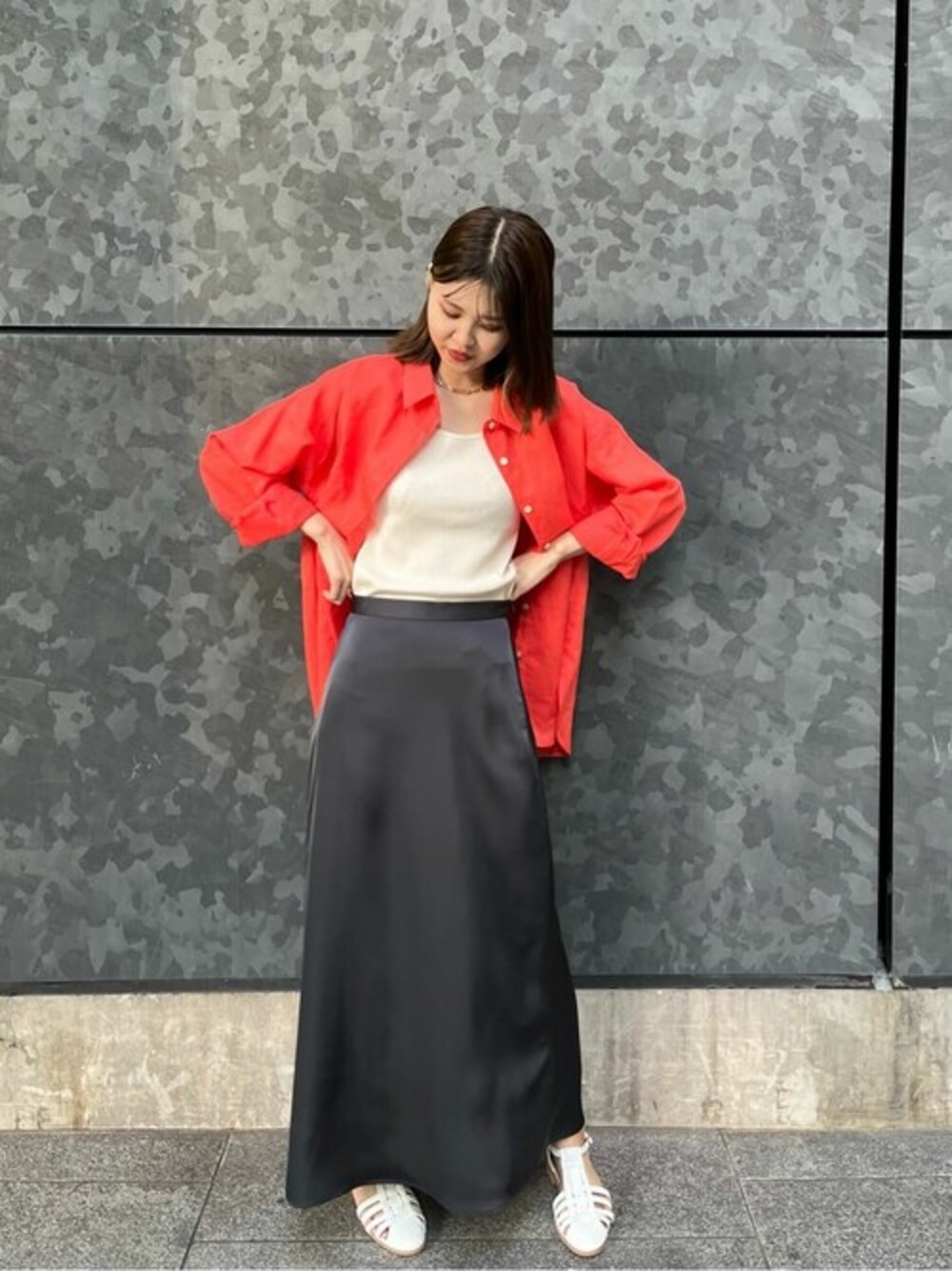 オレンジ系のシャツ/ブラウス、ブラック系のスカート、ホワイト系のタンクトップを着用したレディースの春コーディネートの1枚目の写真