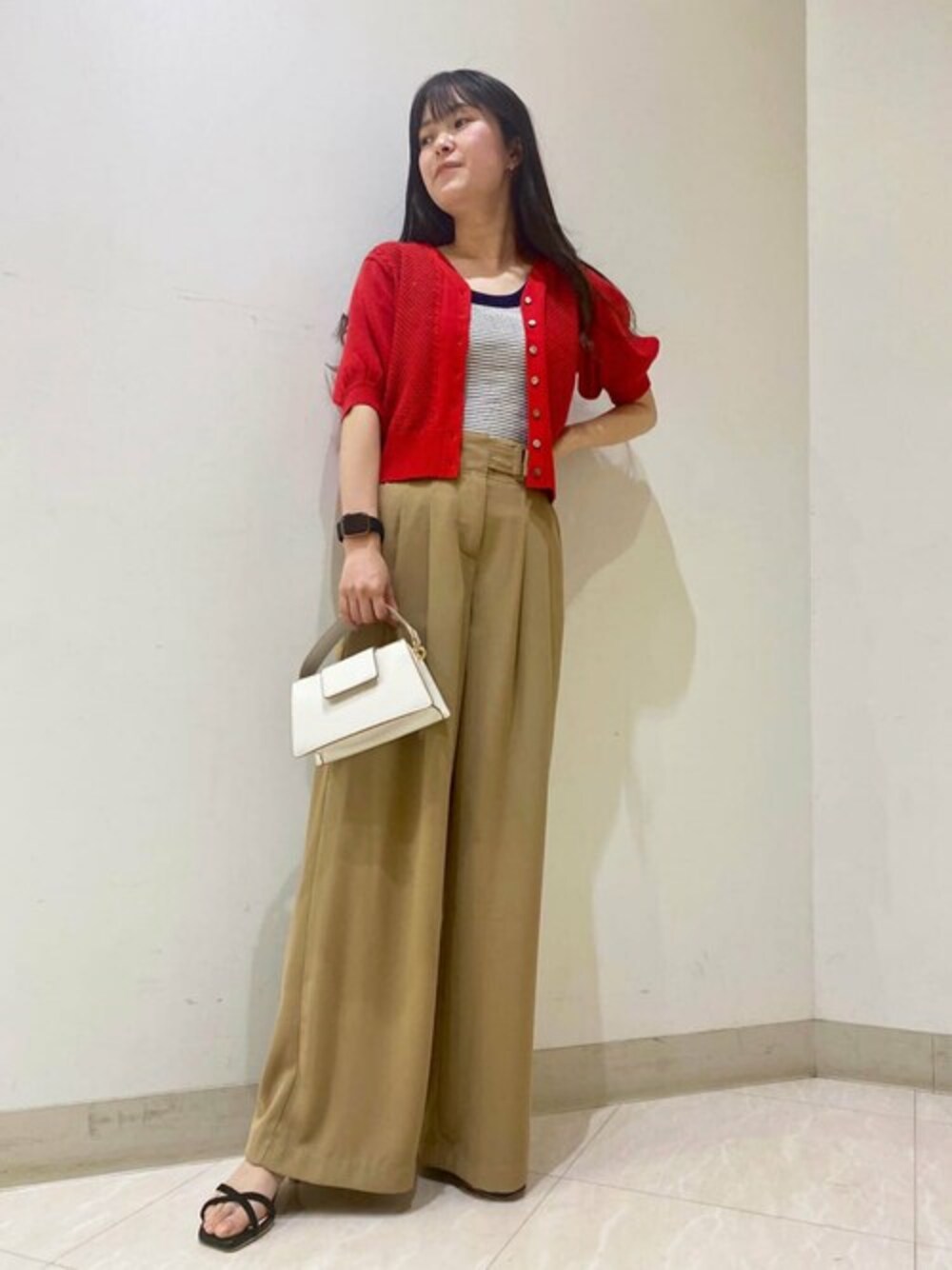 レッド系のカーディガン/ボレロ、ベージュ系のデニムパンツ、ブラック系のサンダルを着用したレディースの春コーディネートの1枚目の写真