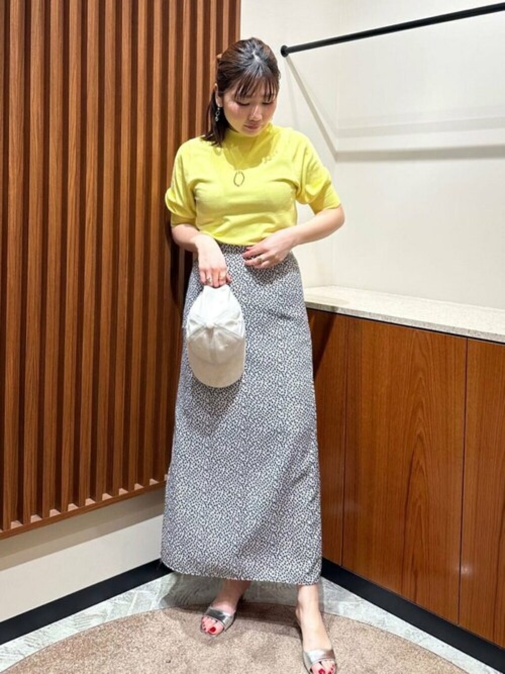 ホワイト系のスカート、イエロー系のニット/セーター、シルバー系のサンダルを着用したレディースの春コーディネートの1枚目の写真