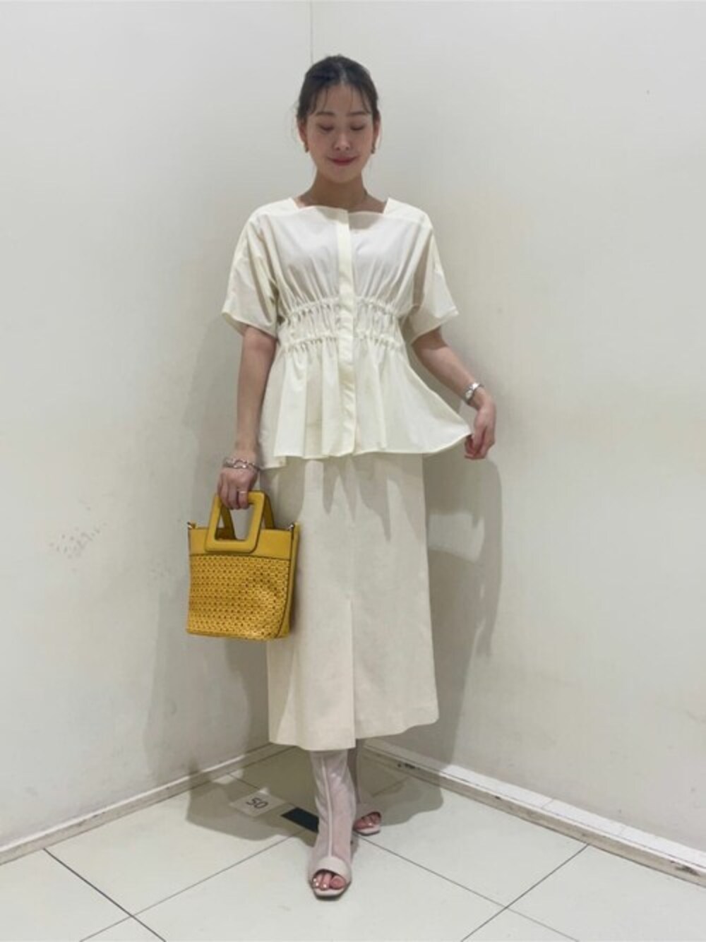 ベージュ系のスカート、イエロー系のトートバッグを着用したレディースの春コーディネートの1枚目の写真