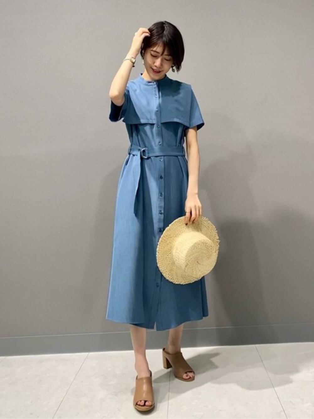 ベージュ系のサンダル、ブルー系のシャツワンピース、ホワイト系のハットを着用したレディースの春コーディネートの1枚目の写真