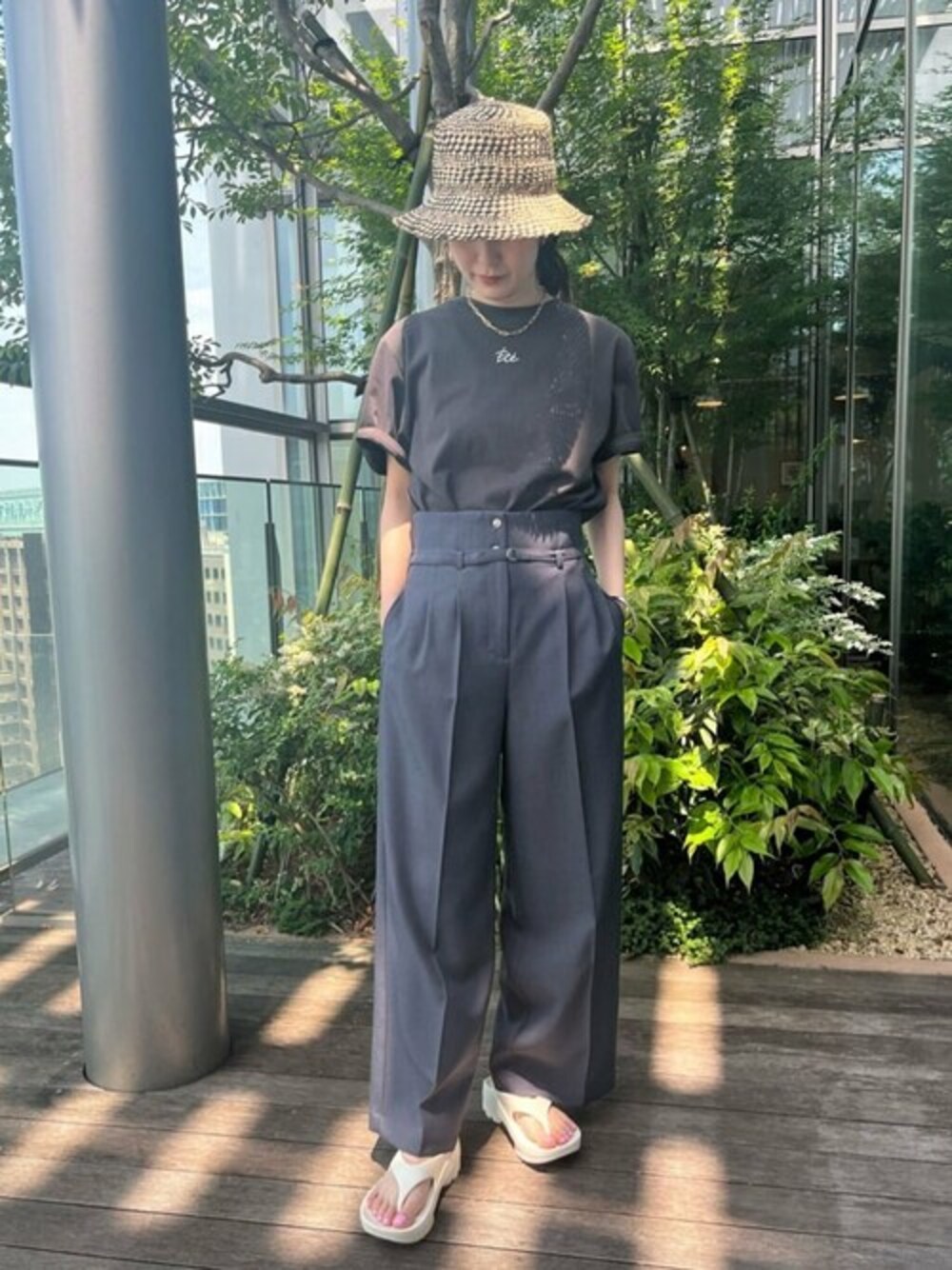 グレー系のスラックス、グレー系のTシャツ/カットソー、ブラック系のハットを着用したレディースの春コーディネートの1枚目の写真