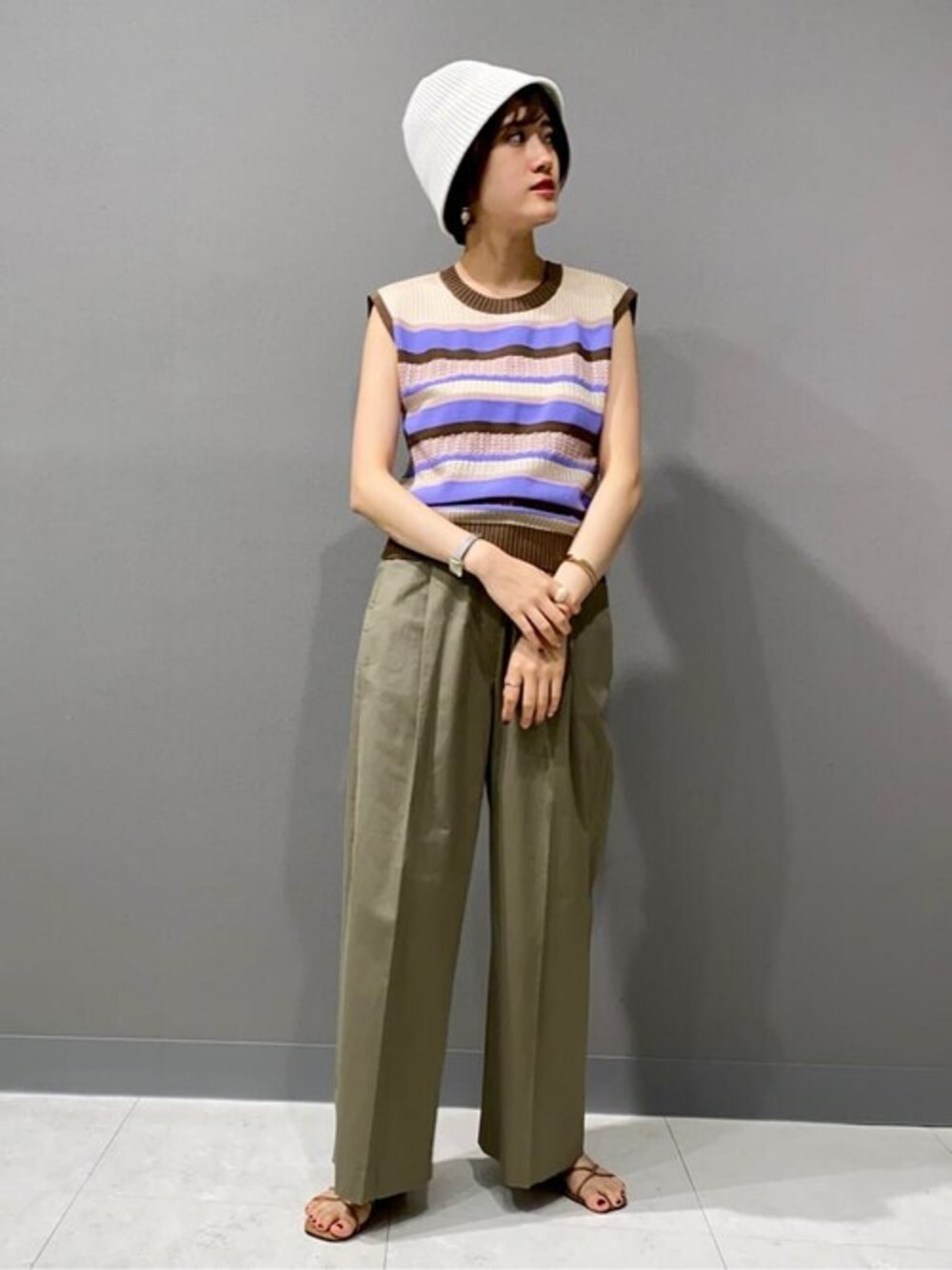 パープル系のニット/セーター、グレー系のスラックス、ホワイト系のハットを着用したレディースの夏コーディネートの1枚目の写真