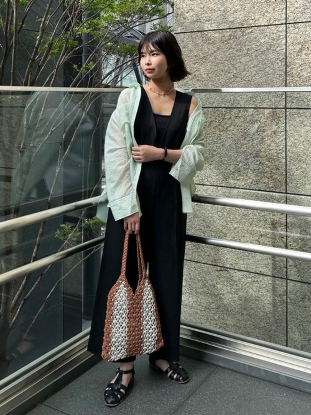 ブラック系のサロペット/オーバーオール、グリーン系のシャツ/ブラウス、ブラック系のサンダルを着用したレディースの夏コーディネートの1枚目の写真