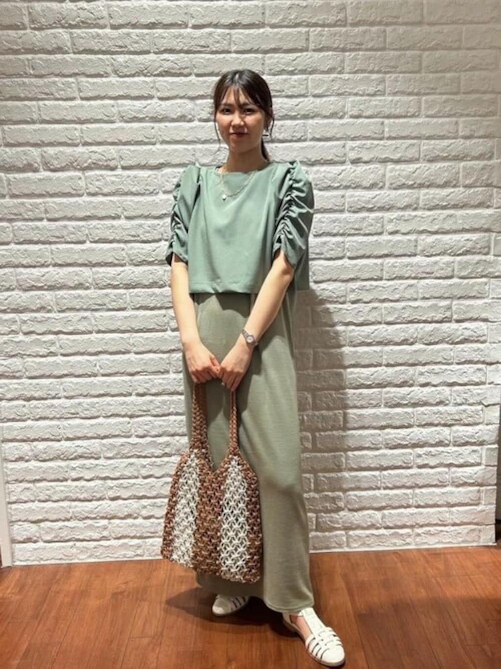 グリーン系のワンピース、ホワイト系のサンダル、オレンジ系のトートバッグを着用したレディースの夏コーディネートの1枚目の写真