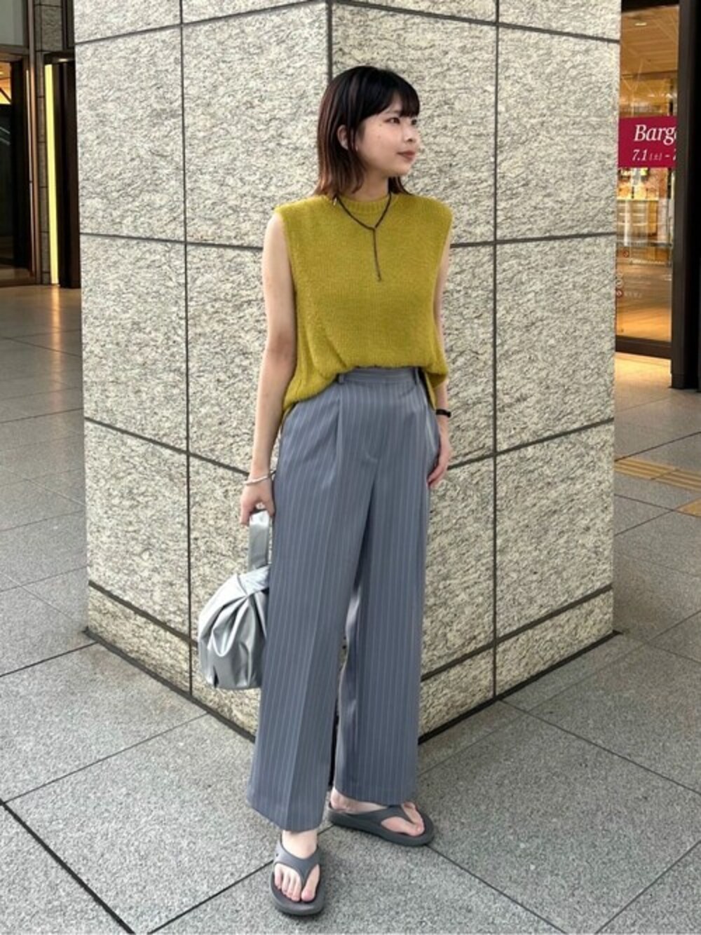 イエロー系のニット/セーター、その他のスラックス、シルバー系のビジネスバッグを着用したレディースの夏コーディネートの1枚目の写真