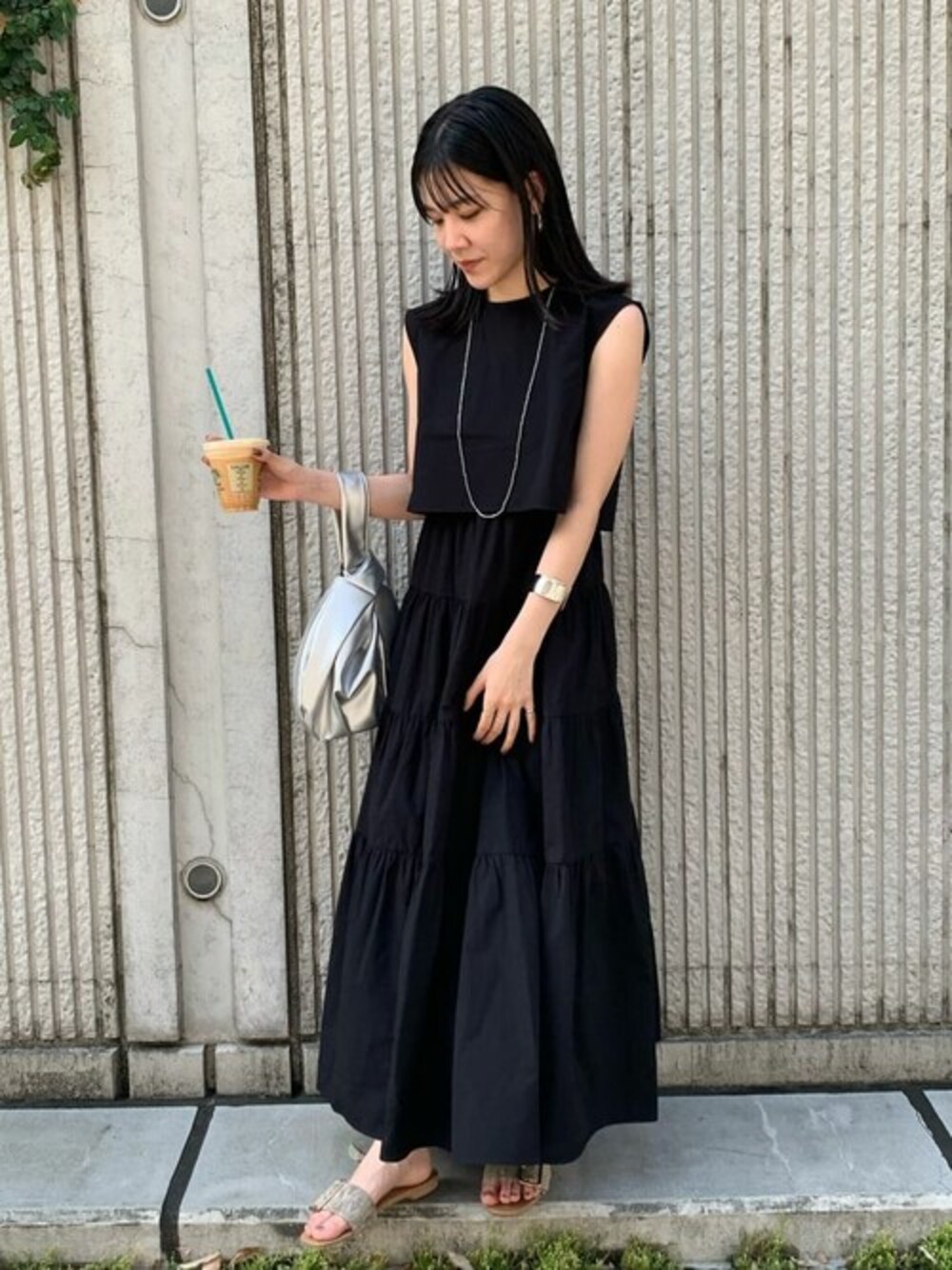 ブラック系のワンピース、ベージュ系のビジネスバッグを着用したレディースの夏コーディネートの1枚目の写真