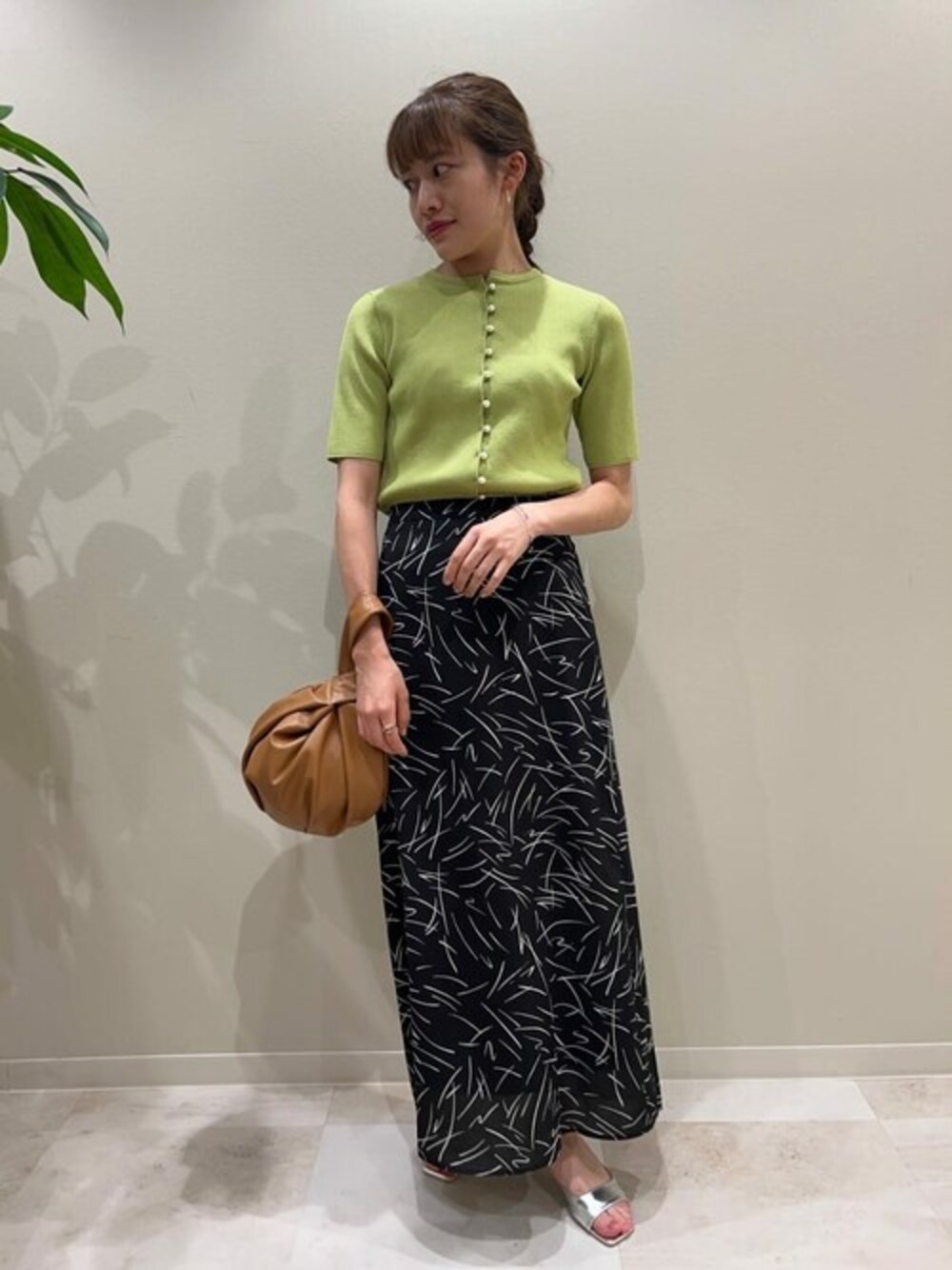 グリーン系のニット/セーター、ブラック系のスカート、シルバー系のサンダルを着用したレディースの夏コーディネートの1枚目の写真