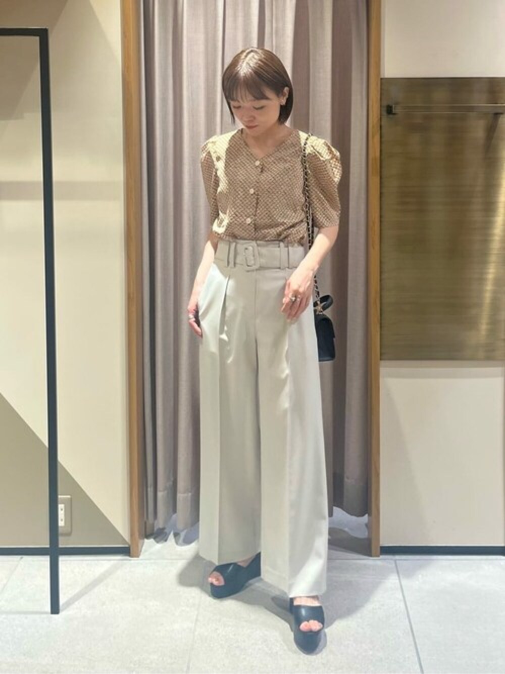 ブラウン系のシャツ/ブラウス、ホワイト系のスラックス、ブラック系のサンダルを着用したレディースの夏コーディネートの1枚目の写真