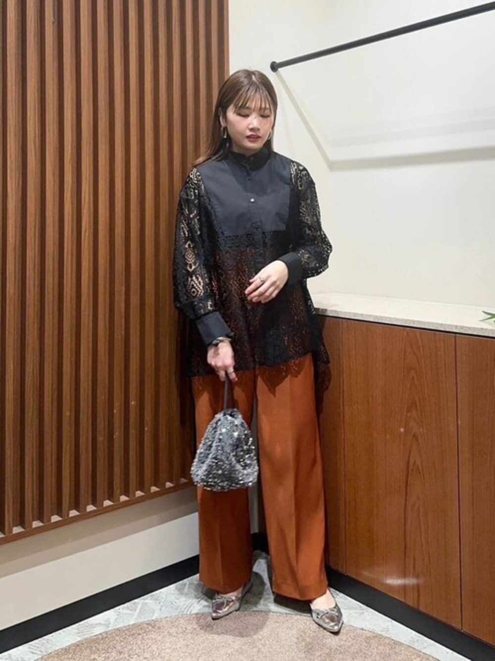 ブラック系のシャツ/ブラウス、オレンジ系のスラックス、グレー系のビジネスバッグを着用したレディースの夏コーディネートの1枚目の写真