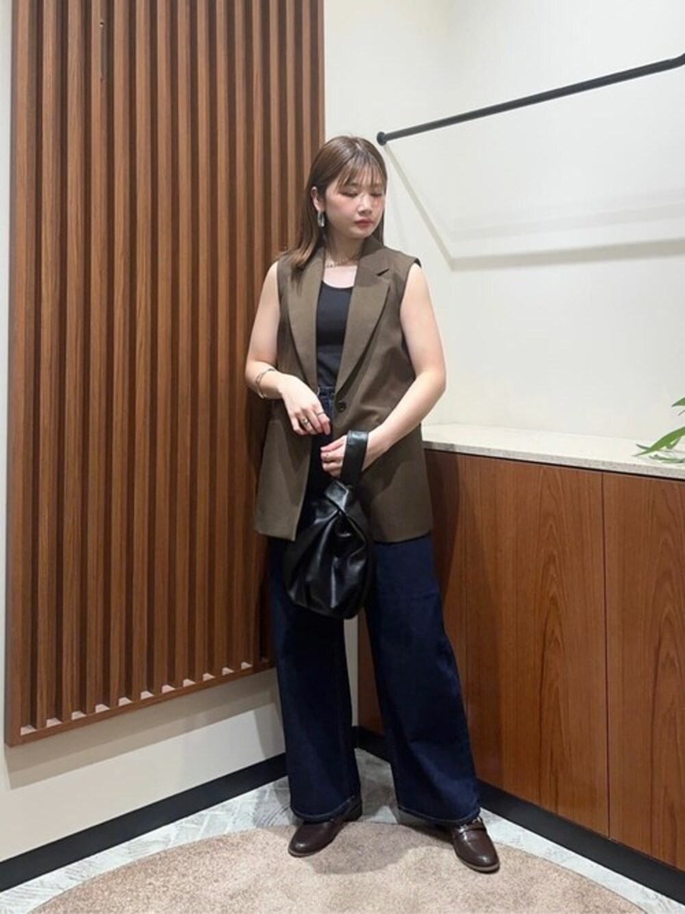 ブラウン系のベスト、ブルー系のデニムパンツ、ブラック系のタンクトップを着用したレディースの夏コーディネートの1枚目の写真