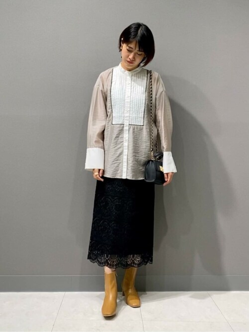 ベージュ系のブーツ、ブラック系のスカート、ベージュ系のシャツ/ブラウスを着用したレディースの秋コーディネートの1枚目の写真