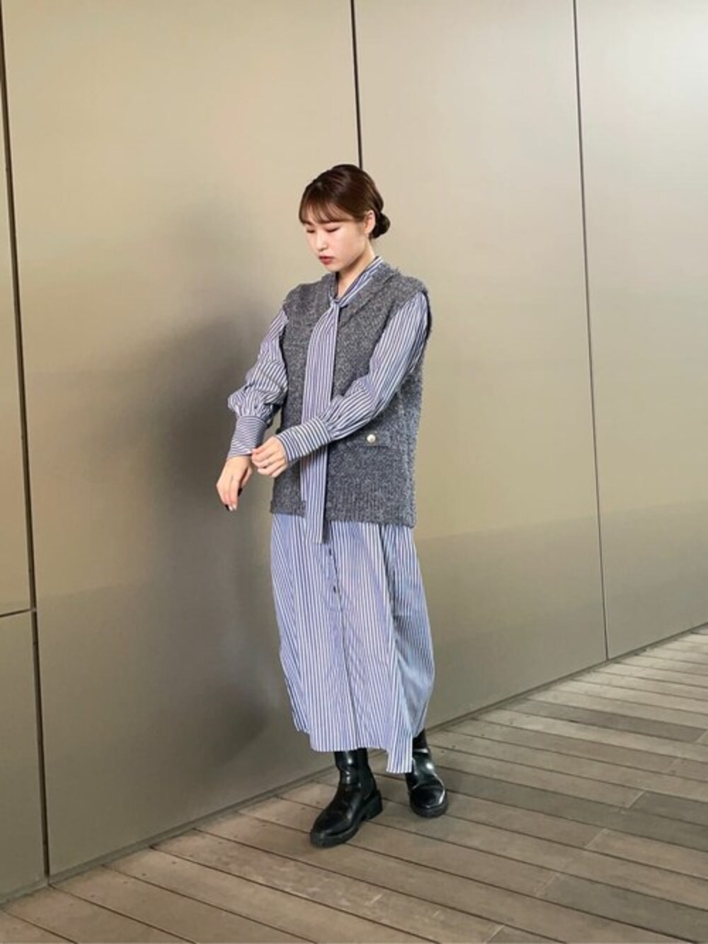 ブルー系のシャツワンピース、グレー系のベスト、ブラック系のブーツを着用したレディースの秋コーディネートの1枚目の写真