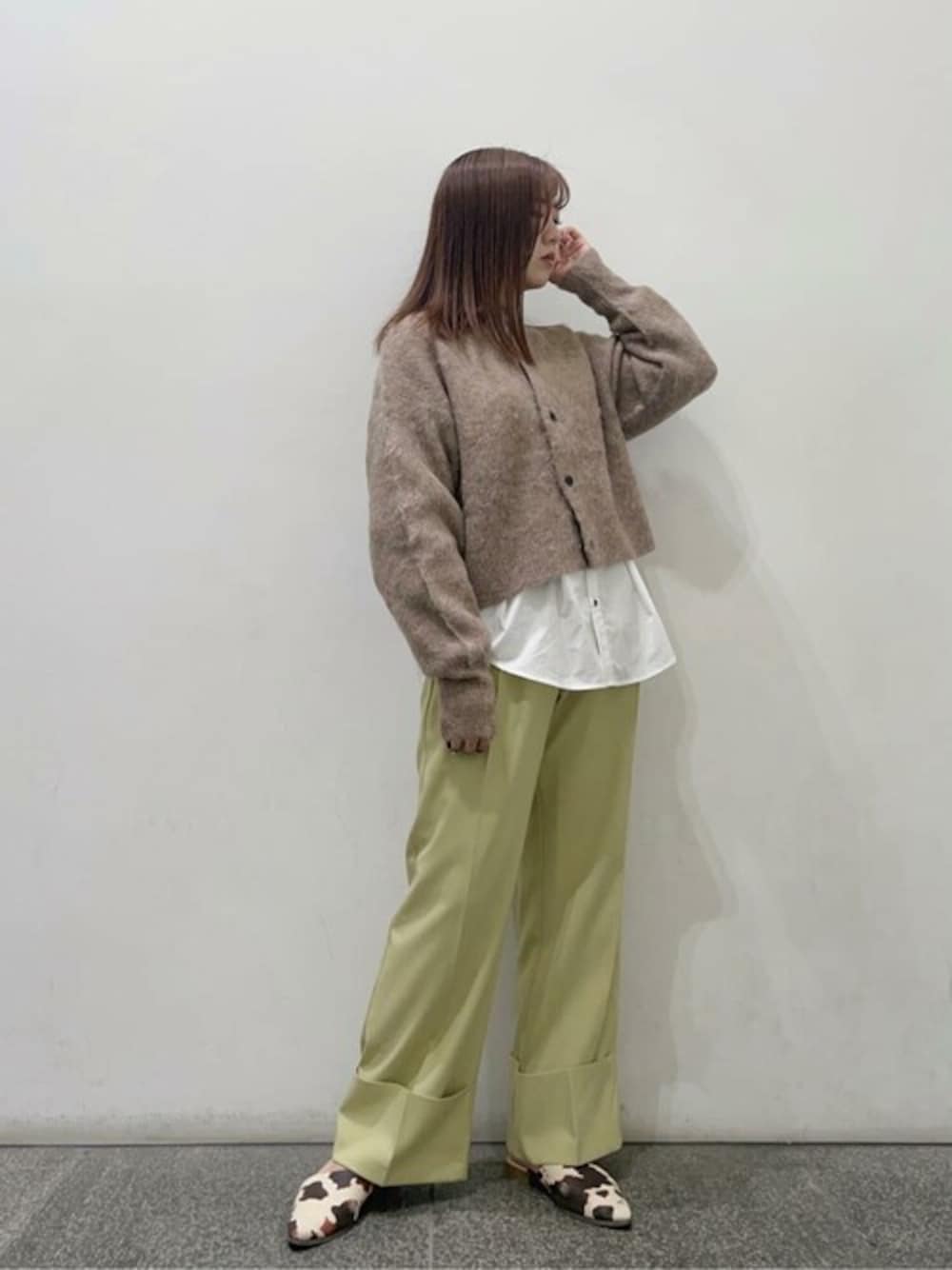 ブラウン系のカーディガン/ボレロ、ホワイト系のシャツ/ブラウス、イエロー系のスラックスを着用したレディースの秋コーディネートの1枚目の写真