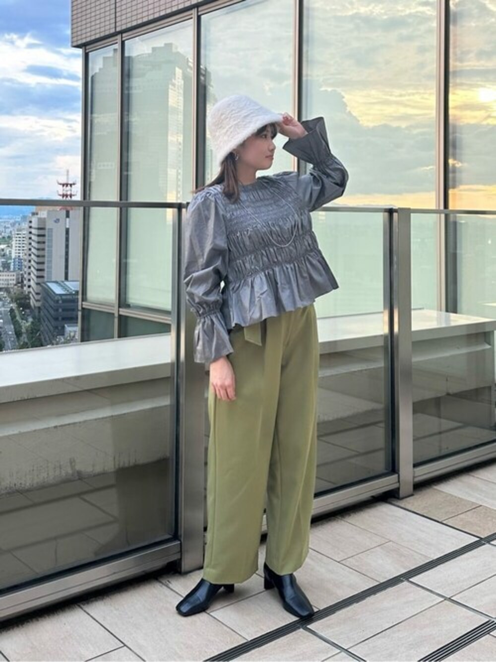 グリーン系のスラックス、ブラック系のブーツ、ホワイト系のハットを着用したレディースの秋コーディネートの1枚目の写真