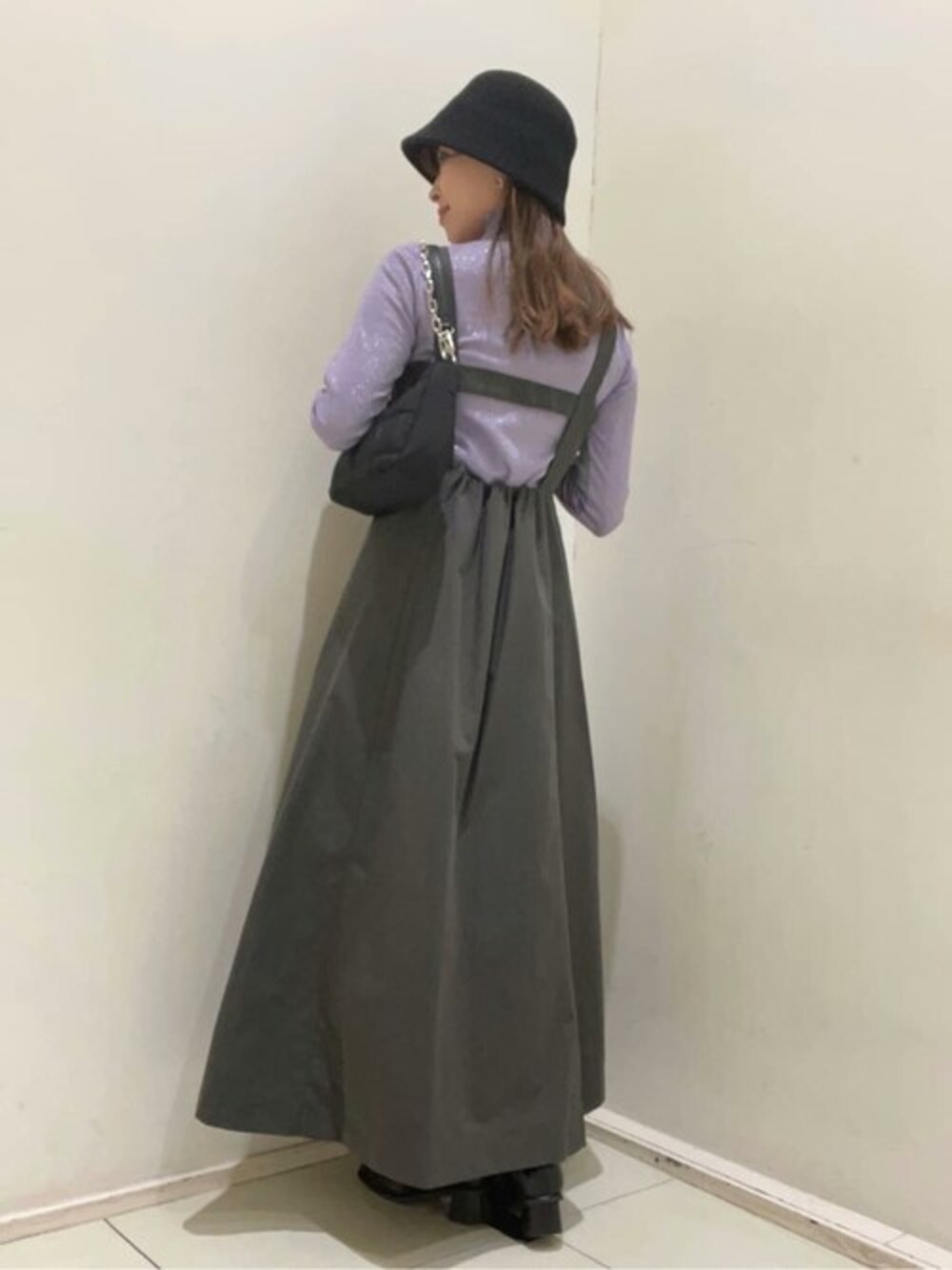 グレー系のジャンパースカート、パープル系のTシャツ/カットソー、ブラック系のブーツを着用したレディースの秋コーディネートの1枚目の写真