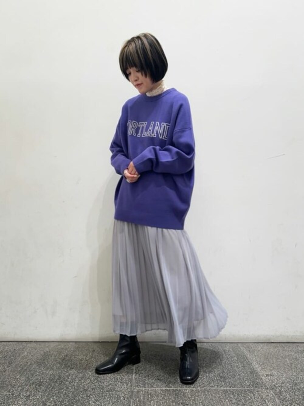 パープル系のニット/セーター、グレー系のスカート、ホワイト系のTシャツ/カットソーを着用したレディースの秋コーディネートの1枚目の写真