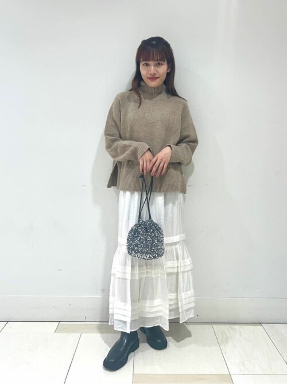ブラウン系のニット/セーター、ホワイト系のスカート、グレー系のビジネスバッグを着用したレディースの秋コーディネートの1枚目の写真