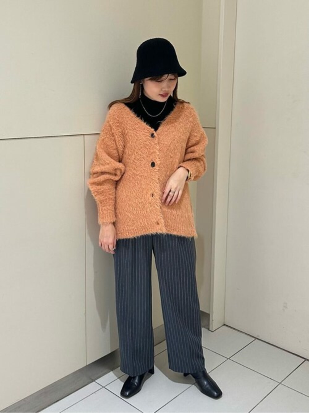 オレンジ系のカーディガン/ボレロ、ブラック系のTシャツ/カットソー、ブラック系のブーツを着用したレディースの秋コーディネートの1枚目の写真