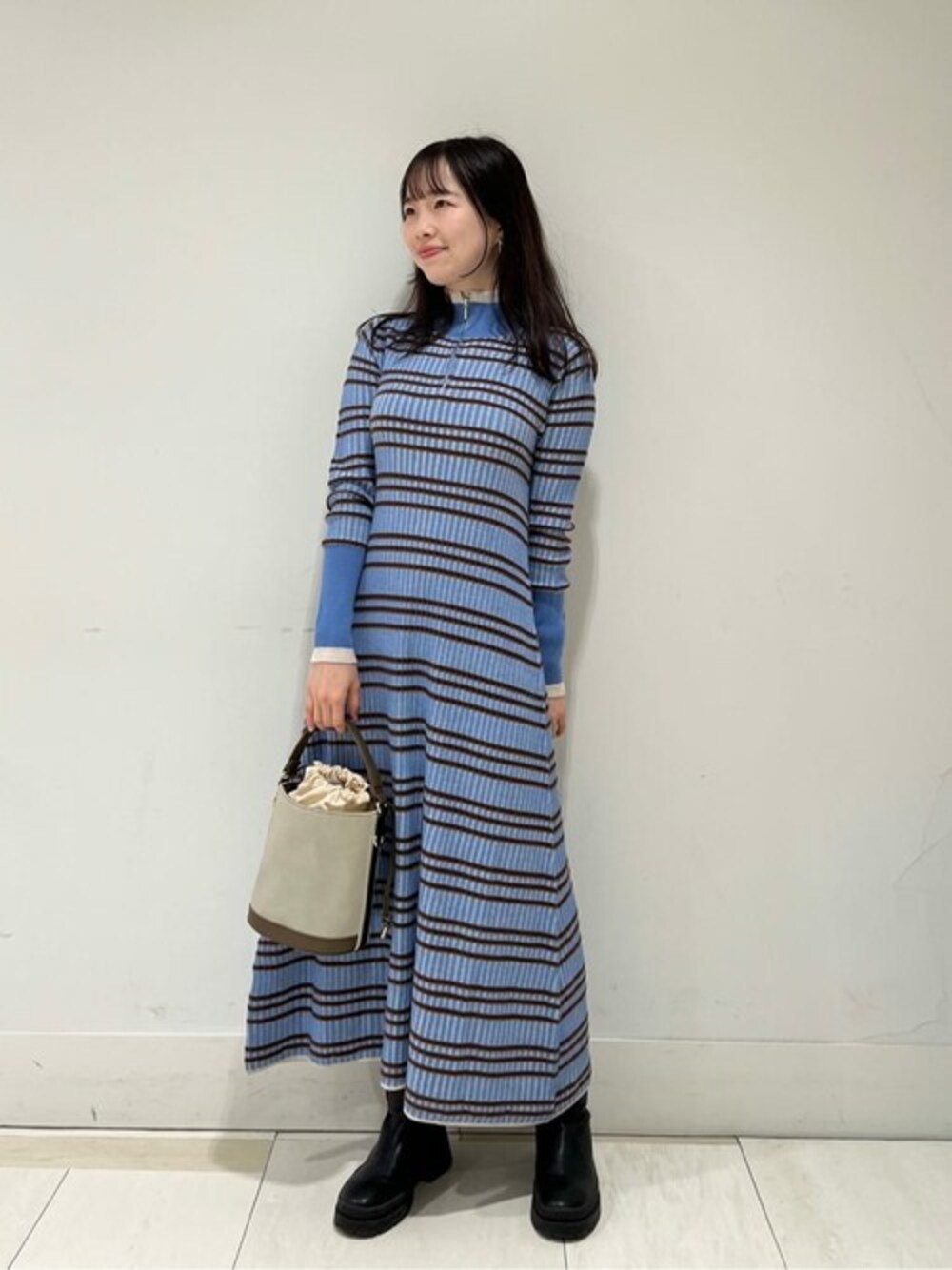 ブルー系のワンピース、グレー系のビジネスバッグ、ブラック系のブーツを着用したレディースの秋コーディネートの1枚目の写真